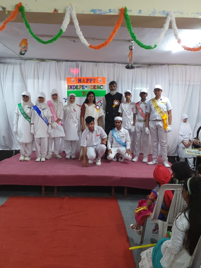 The prefects on stage under the Independence Day board — head girl, head boy, vice captain and the house leads